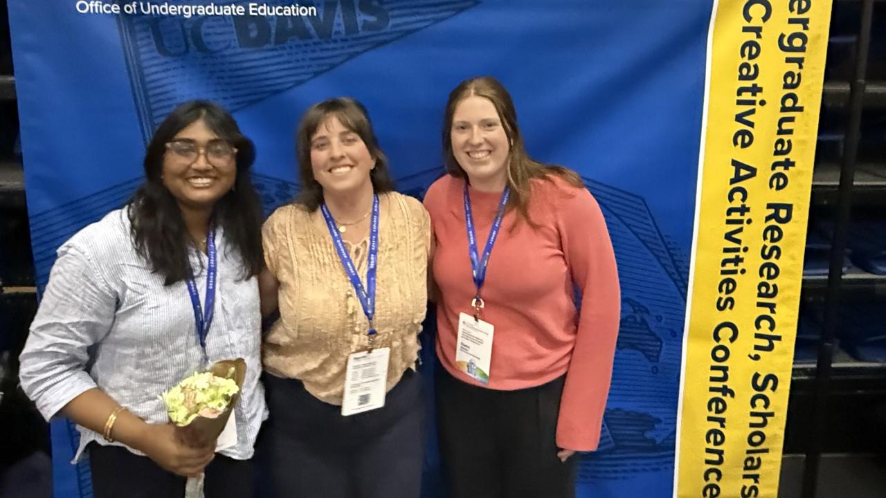 Students stand in front of a banner at the undergraduate research conference
